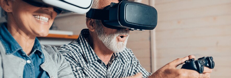 Zwei ältere Männer tragen VR-Headsets und spielen ein Videospiel. Ein Mann hält einen Controller in der Hand und hat einen begeisterten Ausdruck.