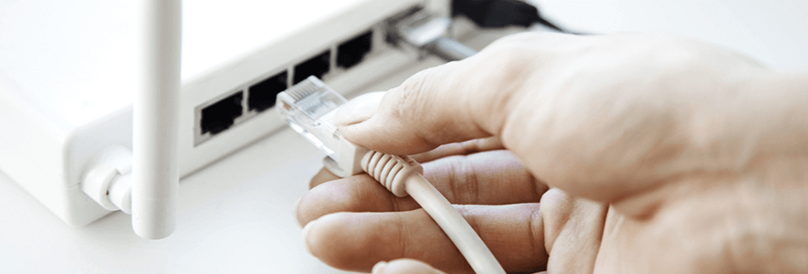Person steckt Kabel in den Glasfaser-Router ein